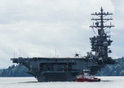 A tug moves the Nimitz down the Rich Passage - USS Nimitz departs for deployment 2017